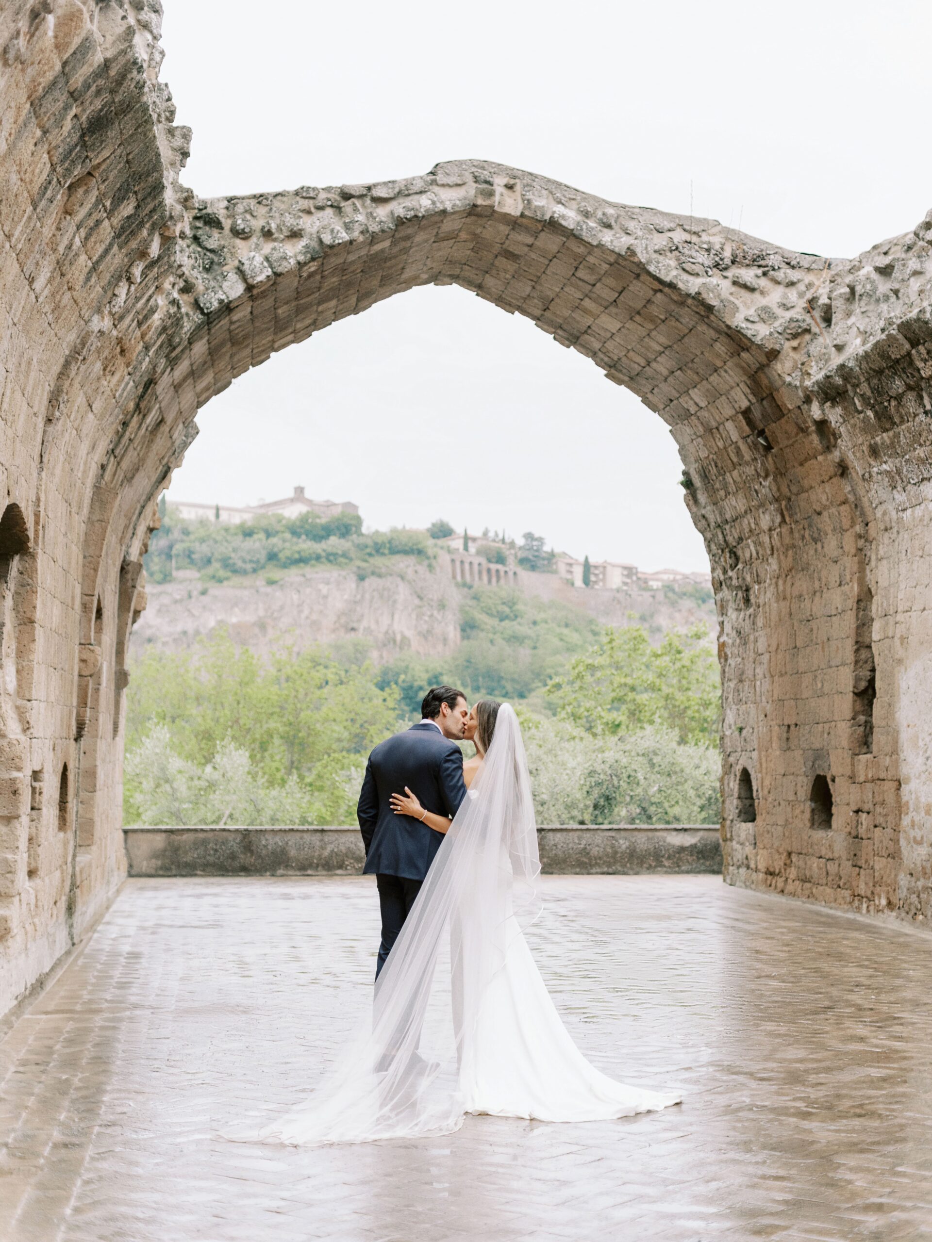 Newlyweds under the ancient arch of La Badia di Orvieto, Umbria